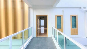 Un interior moderno con barandilla de cristal, pared de listones de madera y suelo de baldosas.