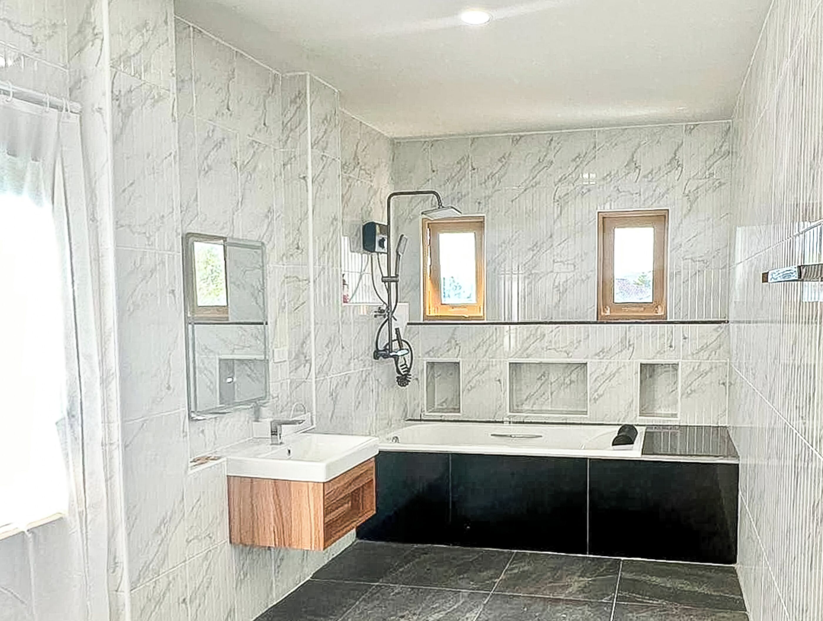 A modern bathroom with a large mirror, a vanity, and a bathtub.