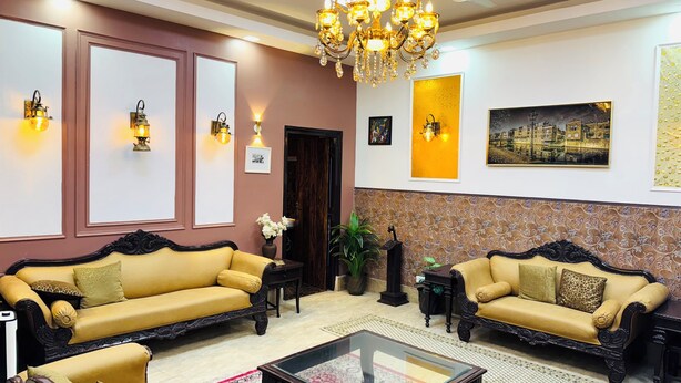 A well-lit living room with two sofas, a glass coffee table, and a chandelier.