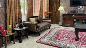 A traditional living room with a sofa, a table with a vase of flowers, a television, and a radio.