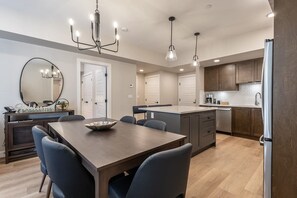 A modern kitchen with a dining area, wooden cabinets, and a large island.