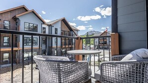 Un bâtiment moderne doté d’un balcon, de chaises en osier et d’une petite table.