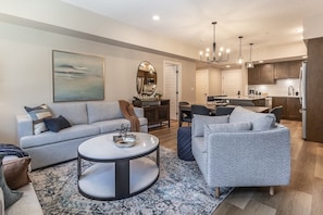 A modern living room with a sofa, a coffee table, and a dining area with chairs.
