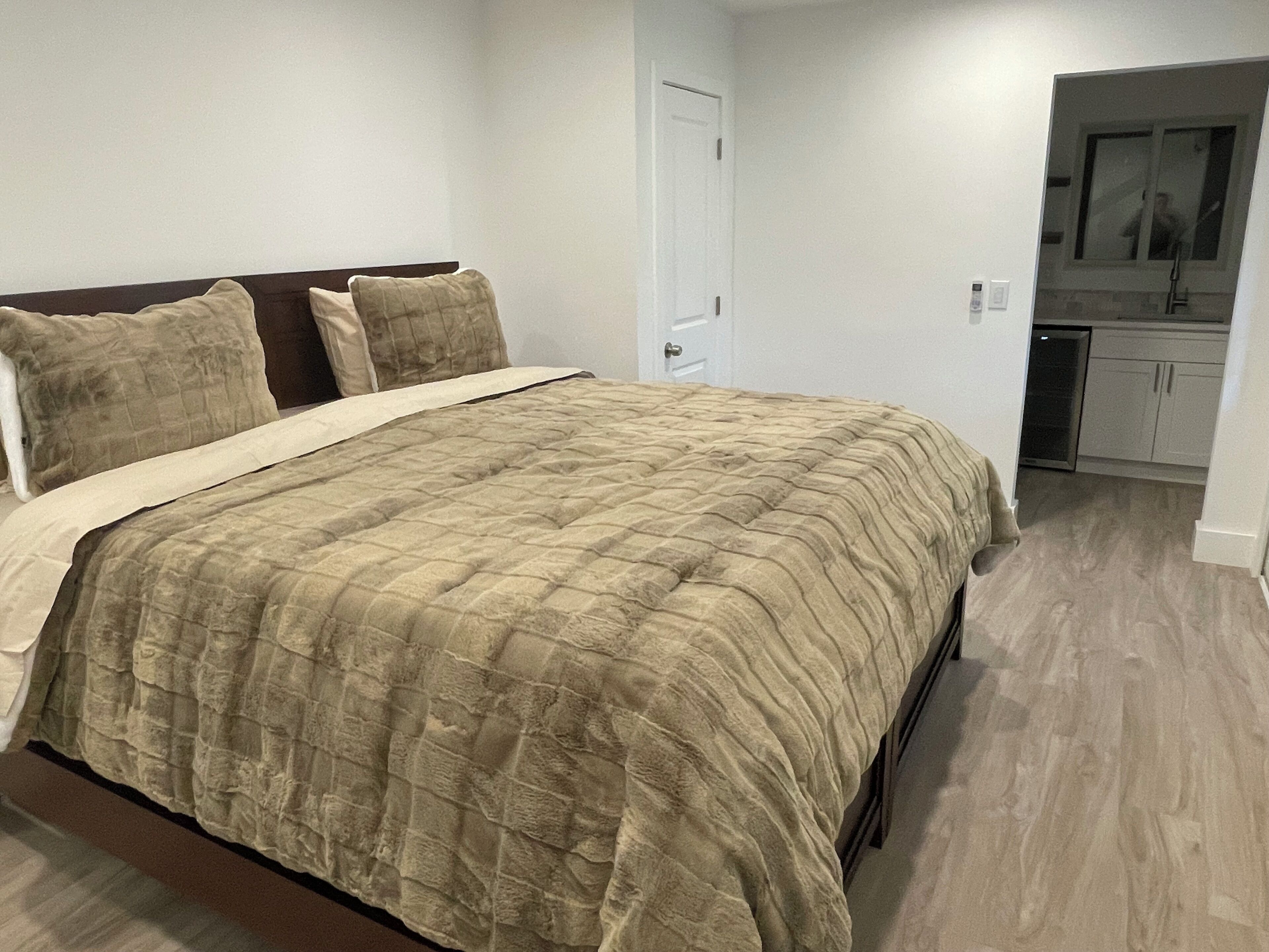 Een slaapkamer met een bed, een deur en een kitchenette.