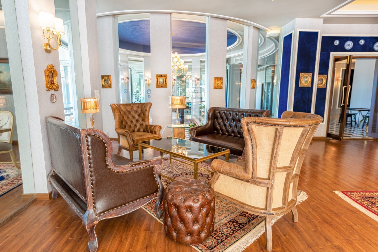 Un lobby lujoso con un muro de cristal curvo, sillones de cuero, un sofá capitonado y una mesa de centro de vidrio.