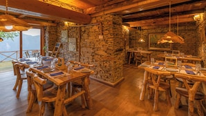 A rustic wooden dining area with stone walls and wooden tables and chairs. - The Manor Wellness & Sport Hotel (Shimla)