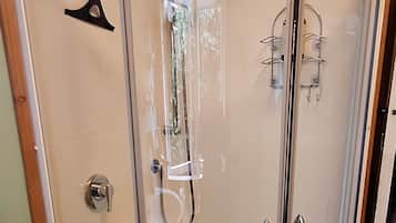 A glass-enclosed shower with a white door, a towel rack, and a showerhead.