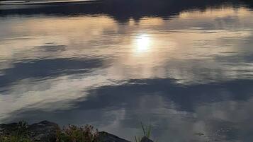 Ein ruhiger See mit einem Berg im Hintergrund und bewölktem Himmel.