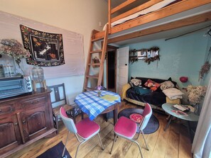 A cozy room with a wooden loft bed, a table with a checkered tablecloth, and a vintage toaster.