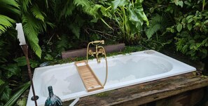 Une baignoire installée dans un jardin luxuriant.