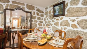 A dining room with a stone wall, wooden furniture, and a painting.