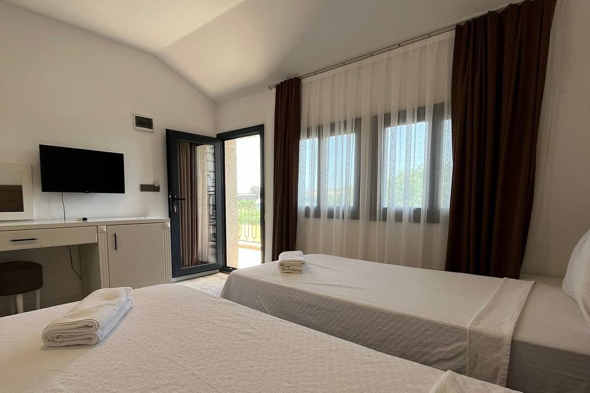 A hotel room with two beds, a desk, and a television.