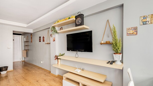 A modern living room with a flat-screen TV, wooden shelves, and a bench. - Cozy Central Flat w/Netflix & Elevator Near Metro 2 minute walking distance (İstanbul)