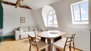 A dining area with a round table, four chairs, a sofa, and a window with a view. - A Glorious 2-Ch/2SdB w/ Services in Saint-Germain (Paris)