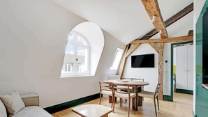 A modern loft apartment with a dining area, a sofa, and a TV mounted on the wall. - A Glorious 2-Ch/2SdB w/ Services in Saint-Germain (Paris)