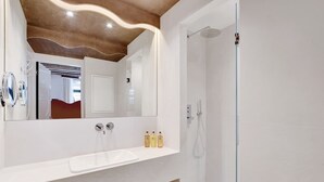 A modern bathroom with a white sink, mirror, and shower.