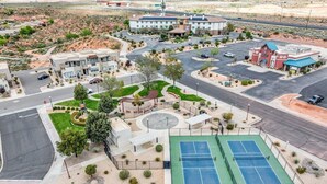 Um hotel com um pátio central, quadras de tênis e estacionamento.