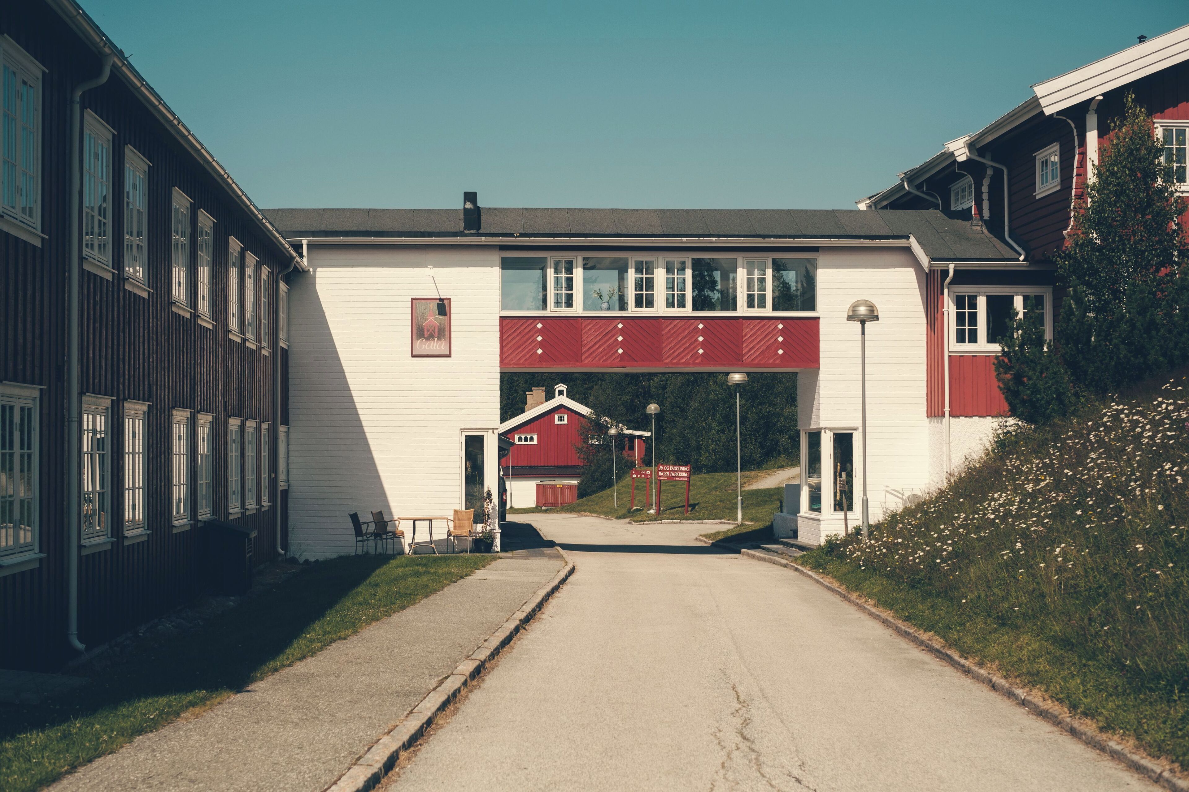 A building with a red and white facade, a covered entrance, and a small outdoor seating area with chairs.