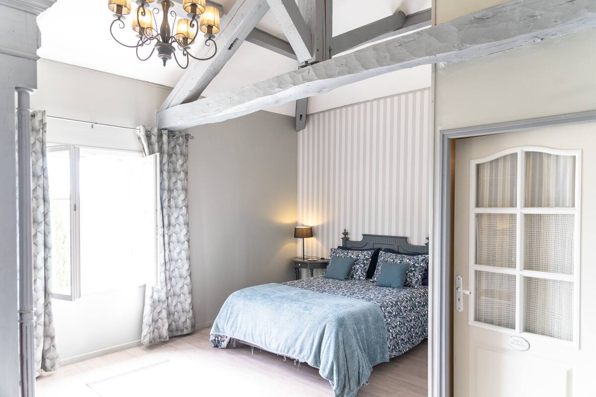 A bedroom with a bed, a nightstand, a lamp, and a window with curtains.