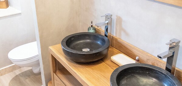 A bathroom with a wooden vanity, a black basin, a white toilet, and a modern faucet. - La Bastide de Canaules (Canaules-et-Argentieres)