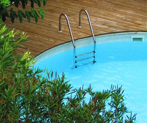 Ein Schwimmbecken mit Holzterrasse und Metallleiter.