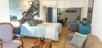 Un dormitorio con una cama, una silla, un sofá, una mesita y un aparador.