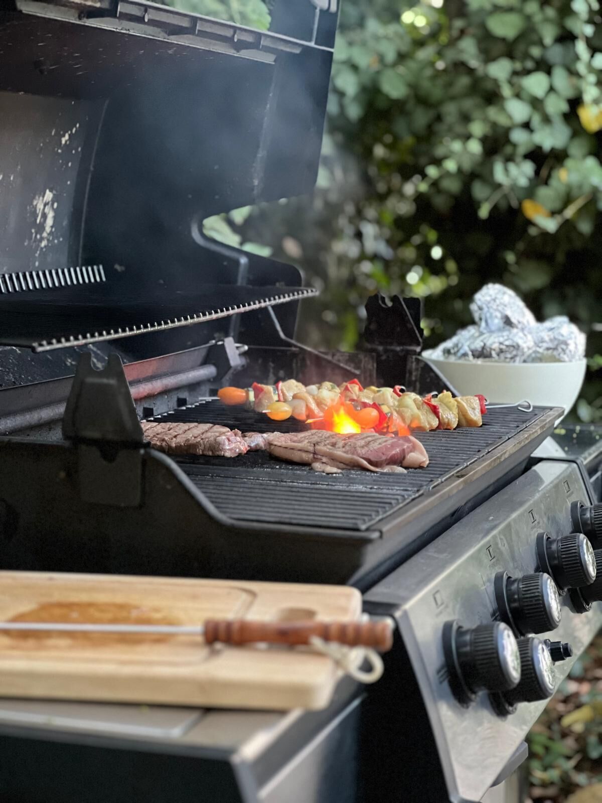 Una parrilla con carne y verduras asándose.