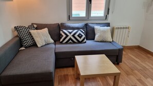 A modern living room with a grey sectional sofa, a wooden coffee table, and patterned throw pillows. - 2 Bed Flat - Sleeps 6 - Pets - Pool - Parking (Vilagarcia de Arousa)