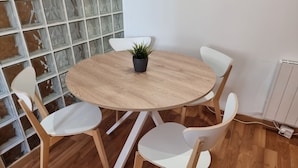 A round wooden table with four white chairs, a potted plant, and a white wall with a window. - 2 Bed Flat - Sleeps 6 - Pets - Pool - Parking (Vilagarcia de Arousa)