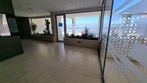 A spacious lobby with tiled floors, potted plants, and a view of a building through glass doors. - 2 Bed Flat - Sleeps 6 - Pets - Pool - Parking (Vilagarcia de Arousa)