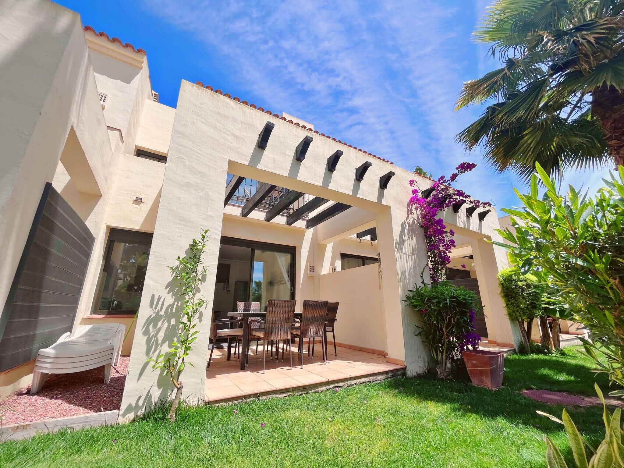 A modern house with a patio, outdoor furniture, and a garden.