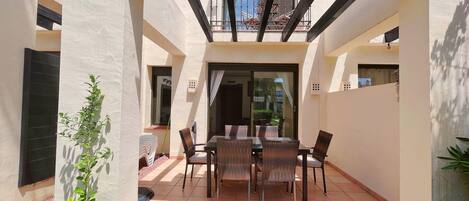 Un patio cubierto con mesa y sillas, una planta pequeña y vistas al exterior.