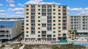Ein mehrstöckiges Hotel mit Balkonen, einem Schwimmbad und Blick auf den Strand.