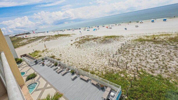 Blick auf einen Strand vom Balkon aus, mit Pool und Liegebereich.