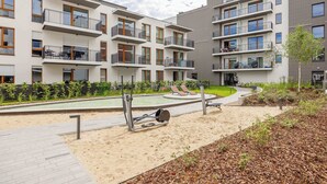 Een modern appartementencomplex met meerdere balkons, een kleine buitenfitnessruimte en een aangelegde tuin.