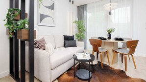 Een moderne woonkamer met een bank, een salontafel en een eethoek met stoelen en een tafel.