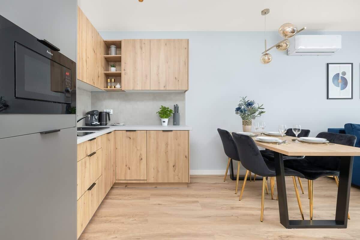 Eine moderne Küche mit Holzschnitzschränken, einem eingebauten Backofen und einem Essbereich mit Tisch und Stühlen.