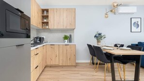 Una cocina moderna con armarios de madera, horno empotrado y comedor con mesa y sillas.