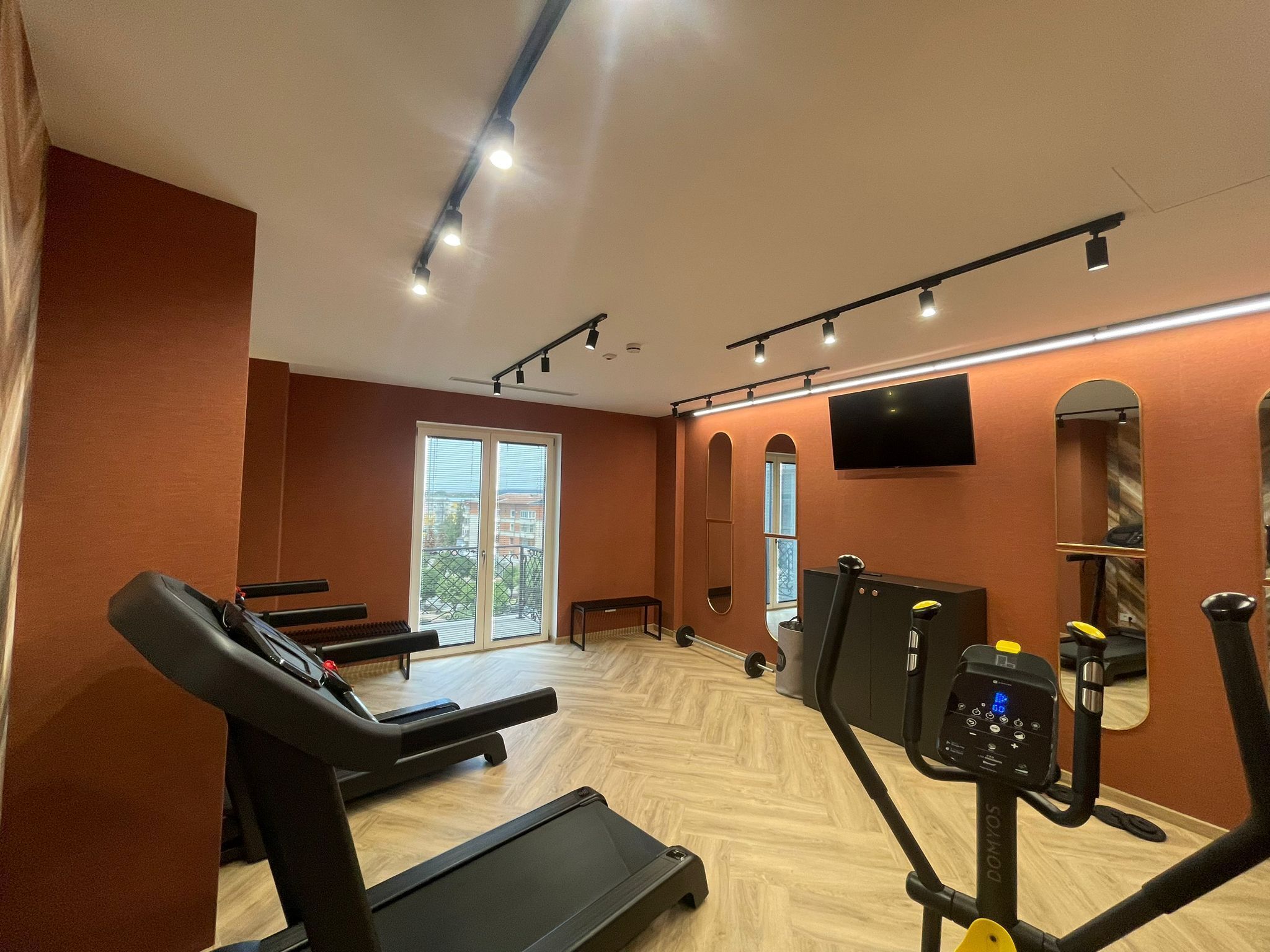 Un gimnasio con cintas de correr, bicicletas estáticas y una pantalla de televisión.