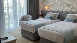 Ein Hotelzimmer mit zwei Betten, einem Schreibtisch und Blick ins Freie.