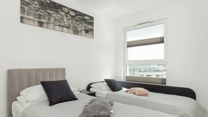 Une chambre d’hôtel moderne avec deux lits, une vue sur la ville et une grande fenêtre.
