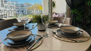 A dining table set with plates, glasses, and cutlery, overlooking a residential area. - Golf Resort - Apartment - Sleeps4 - Pool - Parking (Torre-Pacheco)