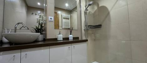 A modern bathroom with a large sink, mirror, and shower.