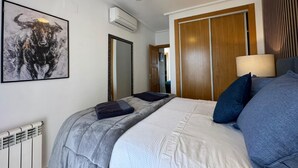 A bedroom with a bed, a ceiling fan, a radiator, a mirror, and a door. - Golf Resort - Apartment - Sleeps4 - Pool - Parking (Torre-Pacheco)
