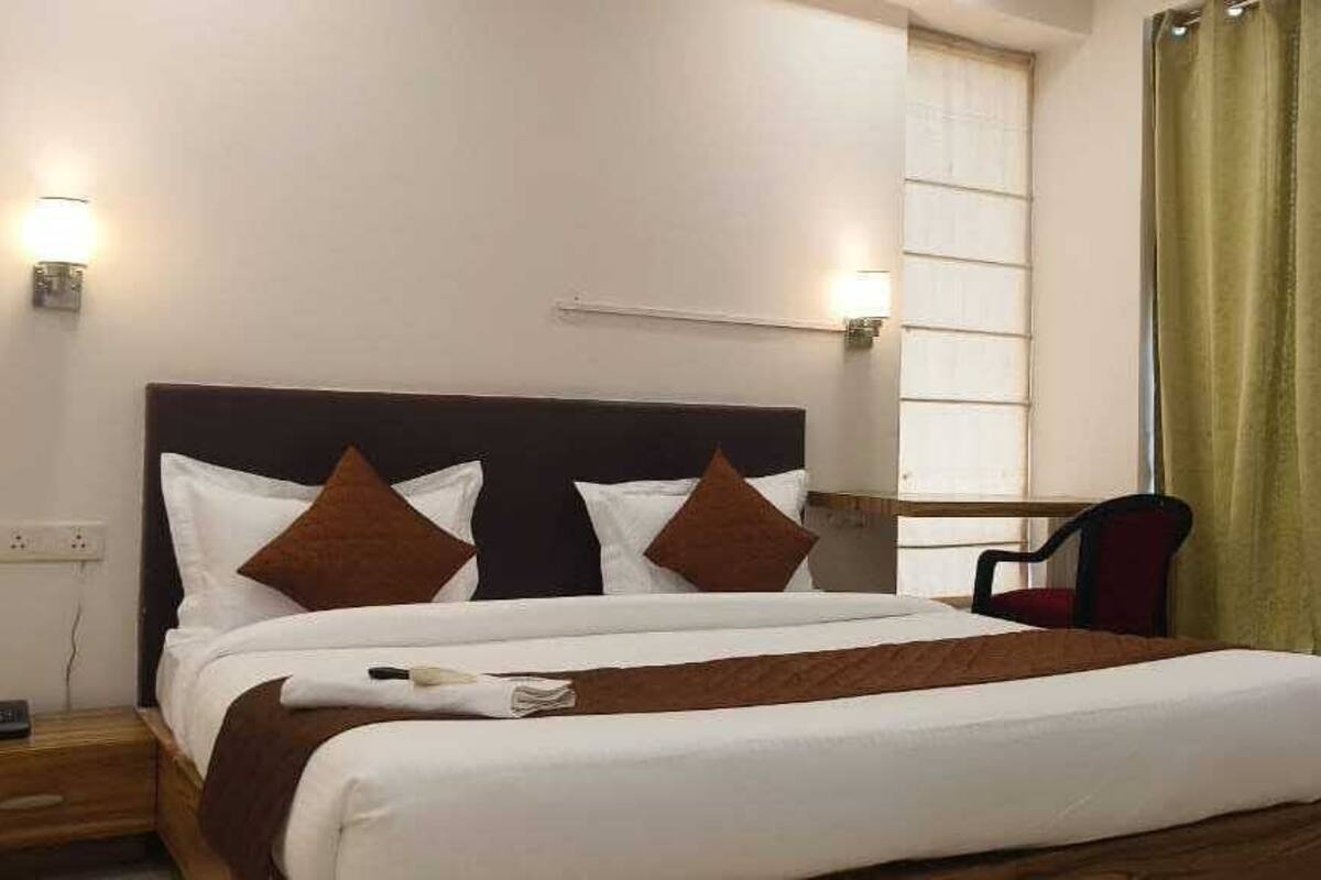 A hotel room with a bed, bedside tables, a chair, and curtains.