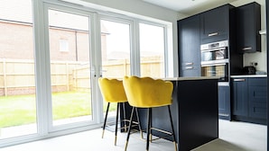 A modern kitchen with dark cabinets, a built-in oven, and a large window. - 3 Bedroom 3.5 Bathroom House Chichester (Chichester)
