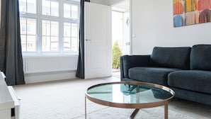 A modern living room with a dark grey sofa, a glass coffee table, and a large window with curtains. - 3 Bedroom 3.5 Bathroom House Chichester (Chichester)