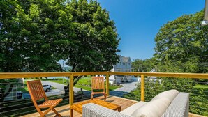 Eine Holzterrasse mit Korbmöbeln und Blick auf eine Wohngegend.