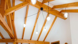 A room with exposed wooden beams, a bed with floral bedding, a dresser, and a wall-mounted light fixture. - At Au Pif: family, hiking, spa bath & nature (Volmunster)