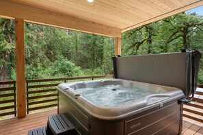 Un bain à remous sur une terrasse en bois, avec vue sur une forêt.